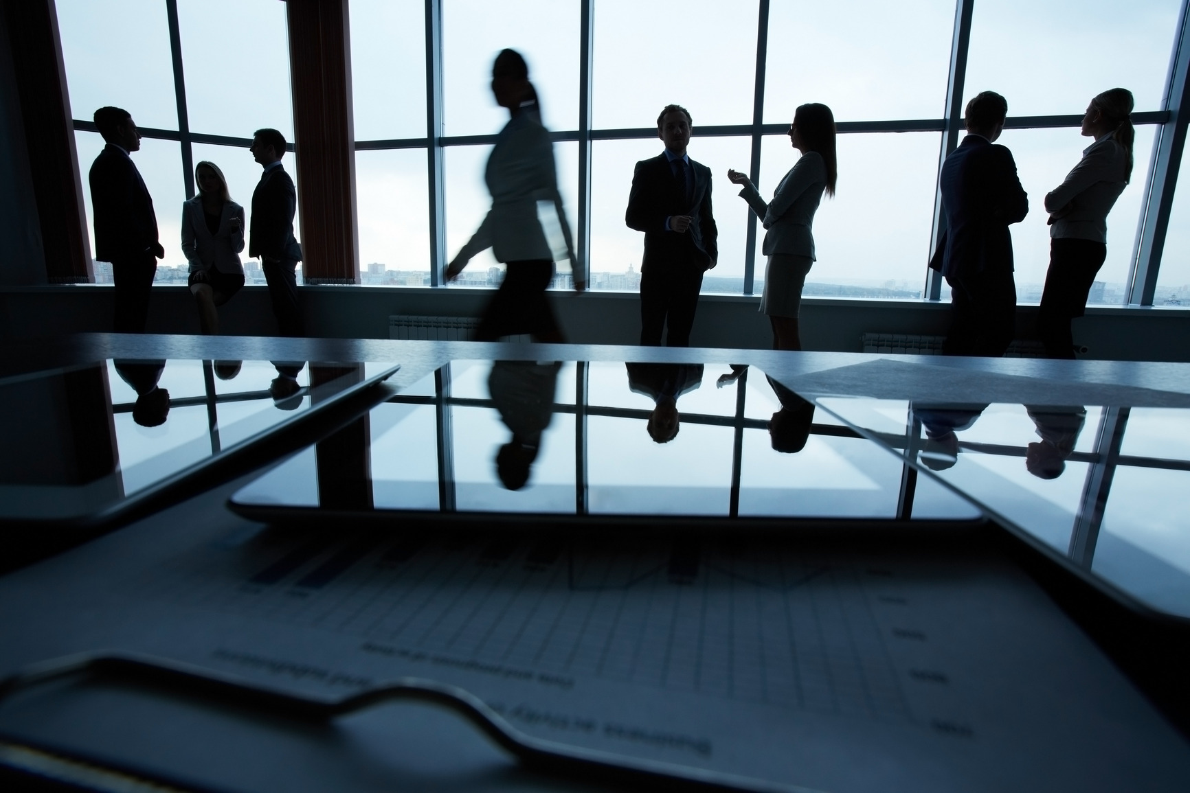 Silhouettes of several office workers on background of window